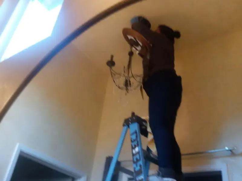 Electrician installing a chandelier in a Tyrone residence